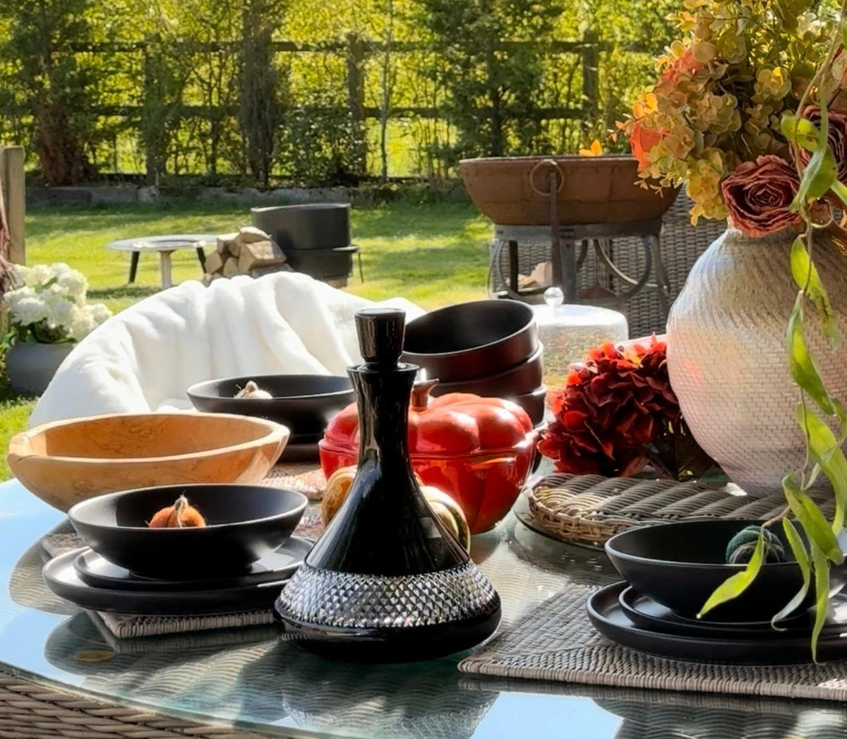 Playa 16-Piece Matte Black Dinnerware Set displayed on an outdoor table decorated with pumpkins and autumn leaves, capturing a cozy fall atmosphere.