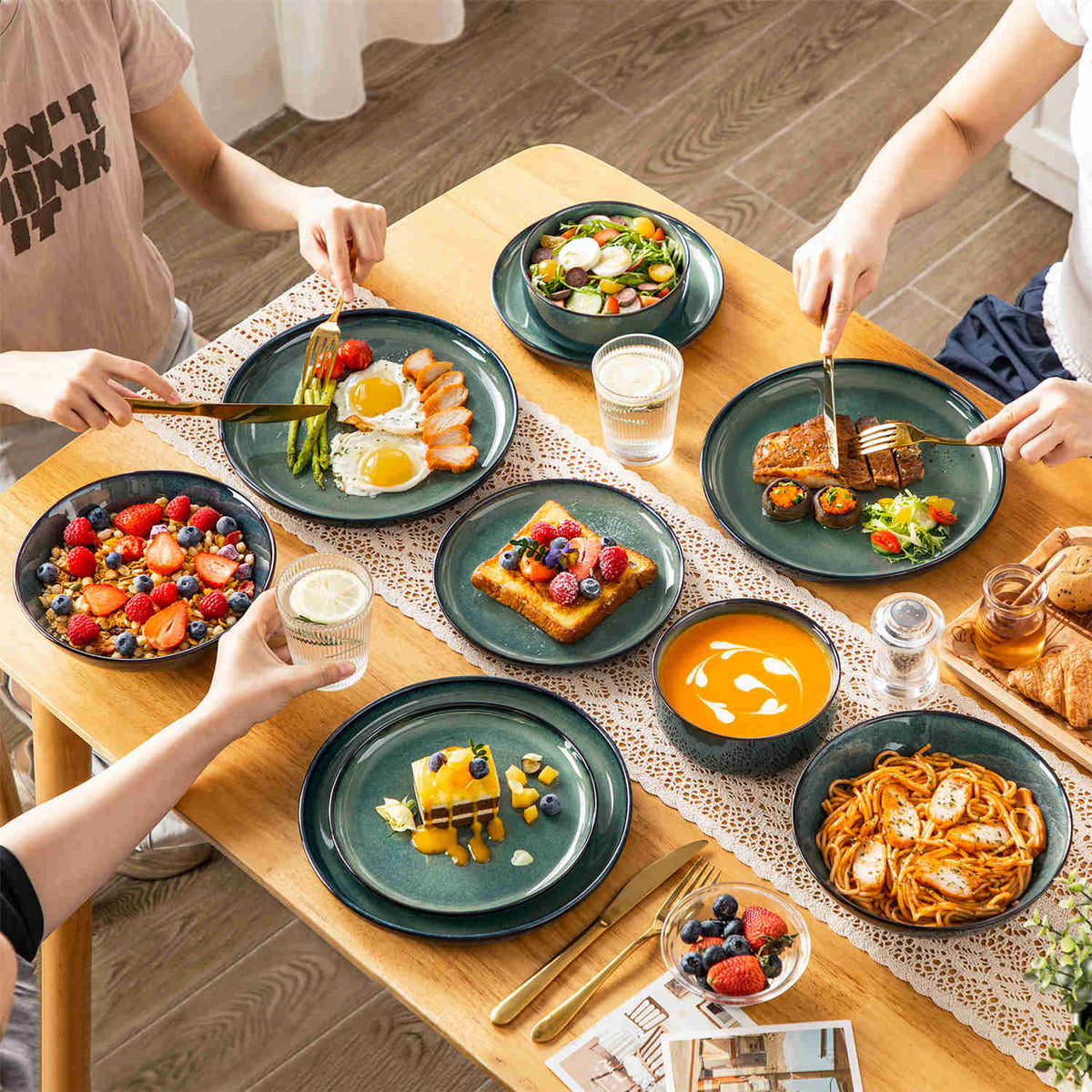 A lush feast on Starry green dinner set: lamb chops, pasta, and fresh berry bowls set against a warm beige table setting.