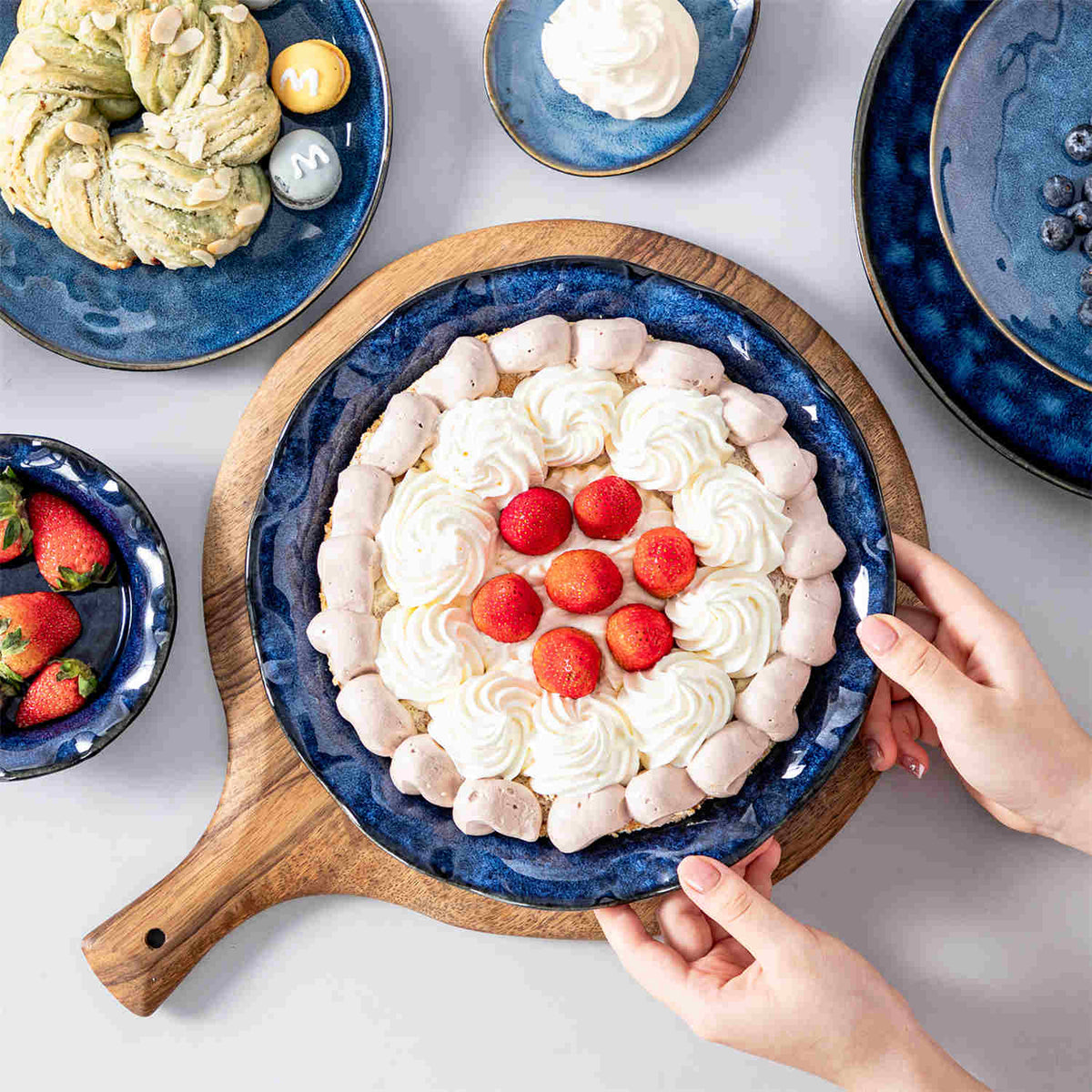 Blue fluted stoneware pie pan with strawberry cream tart, paired with Starry dinnerware on a white dining table.