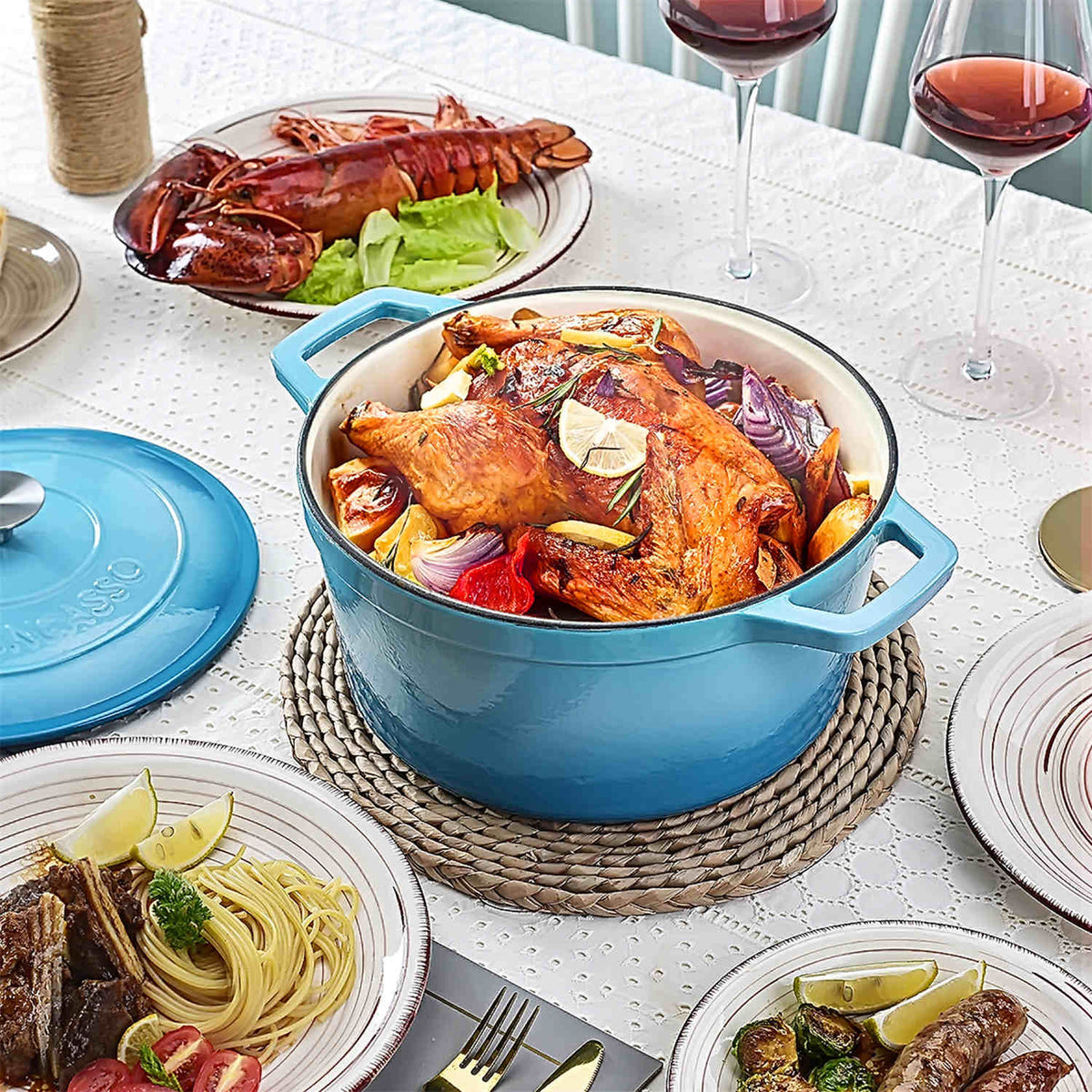 vancasso 6qt enameled cast iron Dutch oven with roast chicken, served alongside baked shrimp with cheese, pasta, lamb chops, and red wine glasses.