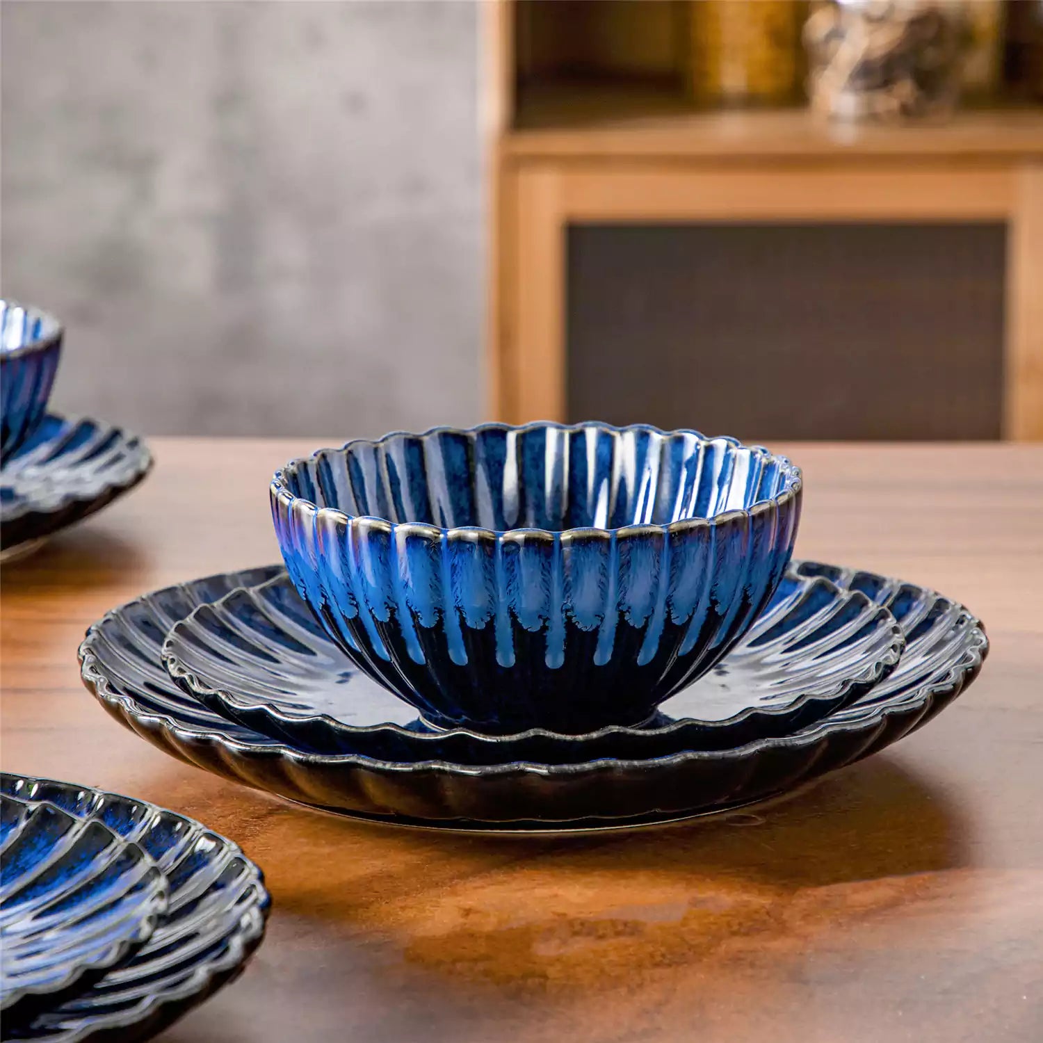 Blue reactive glaze stoneware bowls and plates from the Adonis 12 piece set with brown placemats and fresh flowers