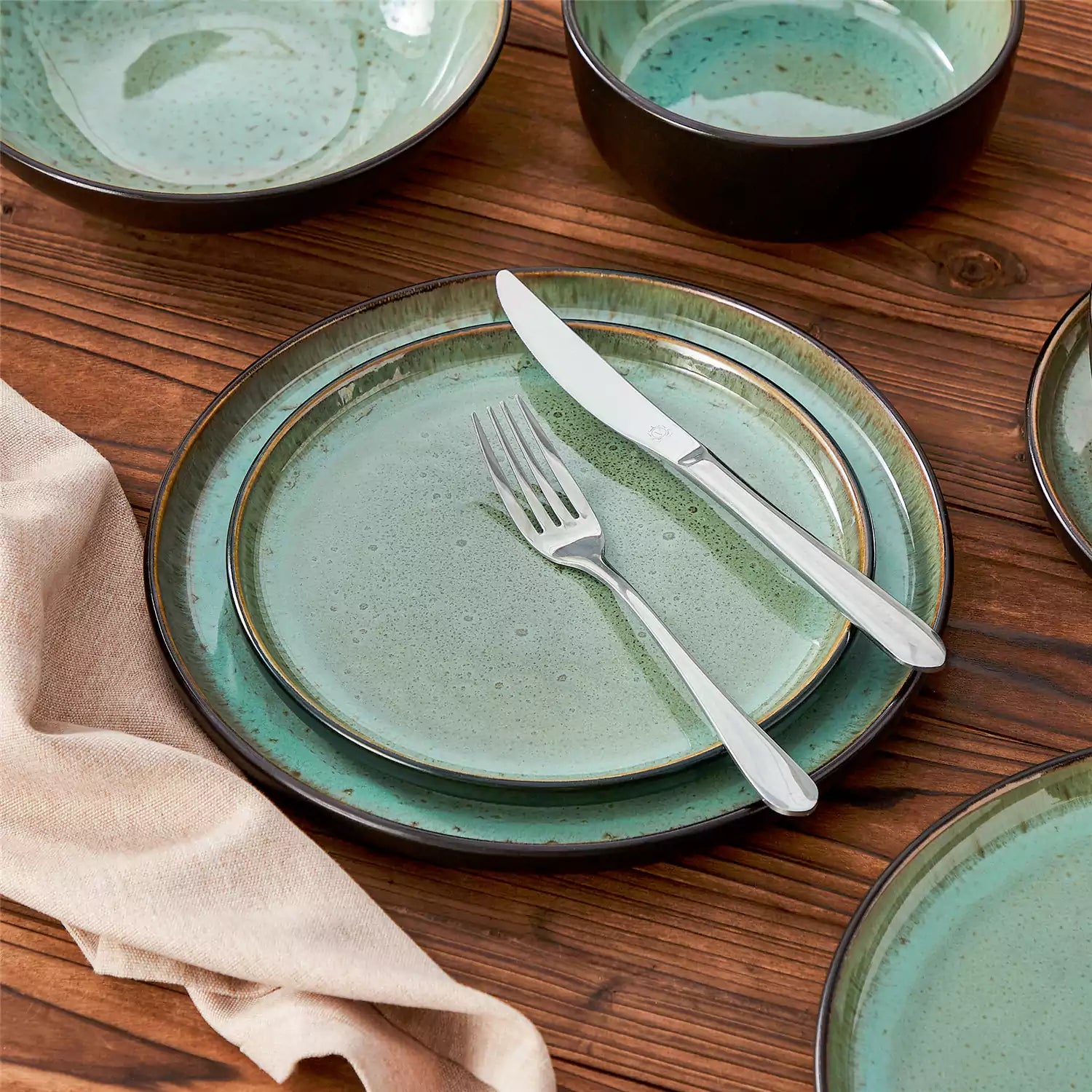 Rustic dining table with Amber 12-piece stoneware dinnerware in farmhouse green - featuring reactive glaze plates - bowls - and utensils by vancasso