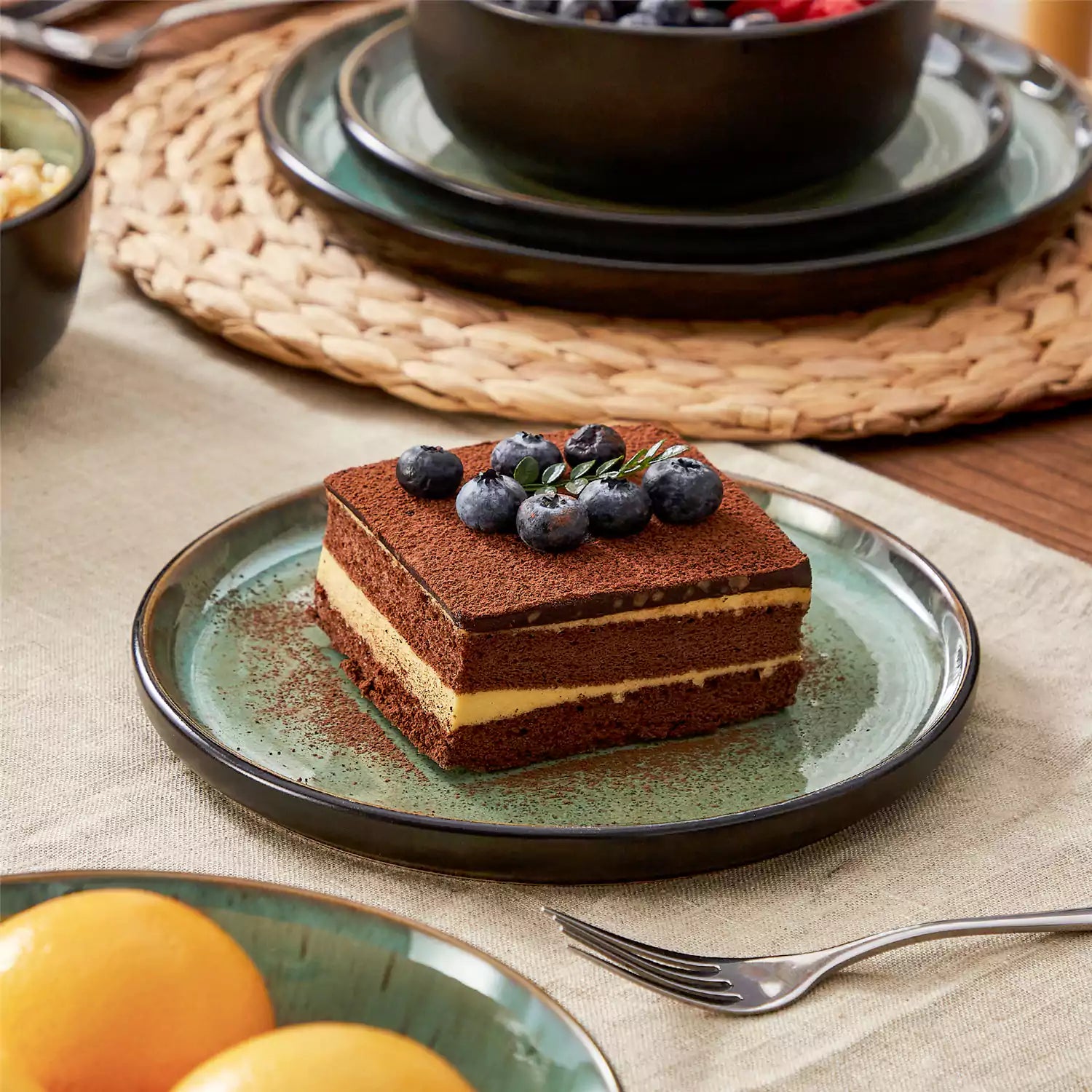 Assorted dishes with soup - dessert - and fruit salad on rustic wooden table - Amber 16-Piece green stoneware dinnerware set with plates and bowls by vancasso