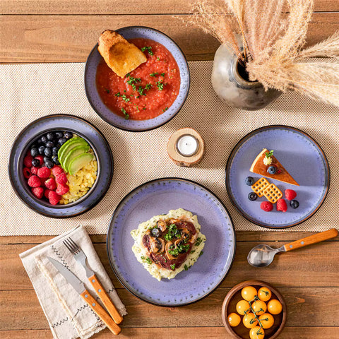 Assorted dishes with soup - dessert - and fruit salad on rustic wooden table - Amber 16-Piece violet stoneware dinnerware set with plates and bowls by vancasso