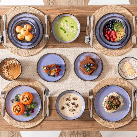 Assorted dishes with soup - dessert - and fruit salad on rustic wooden table - Amber 16-Piece violet stoneware dinnerware set with plates and bowls by vancasso