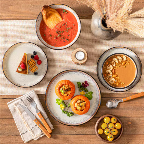 Assorted dishes with soup - dessert - and fruit salad on rustic wooden table - Amber 16-Piece beige stoneware dinnerware set with plates and bowls by vancasso