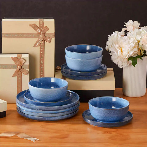 Blue stoneware plates and bowls with reactive glaze on farmhouse wooden table with woven placemats