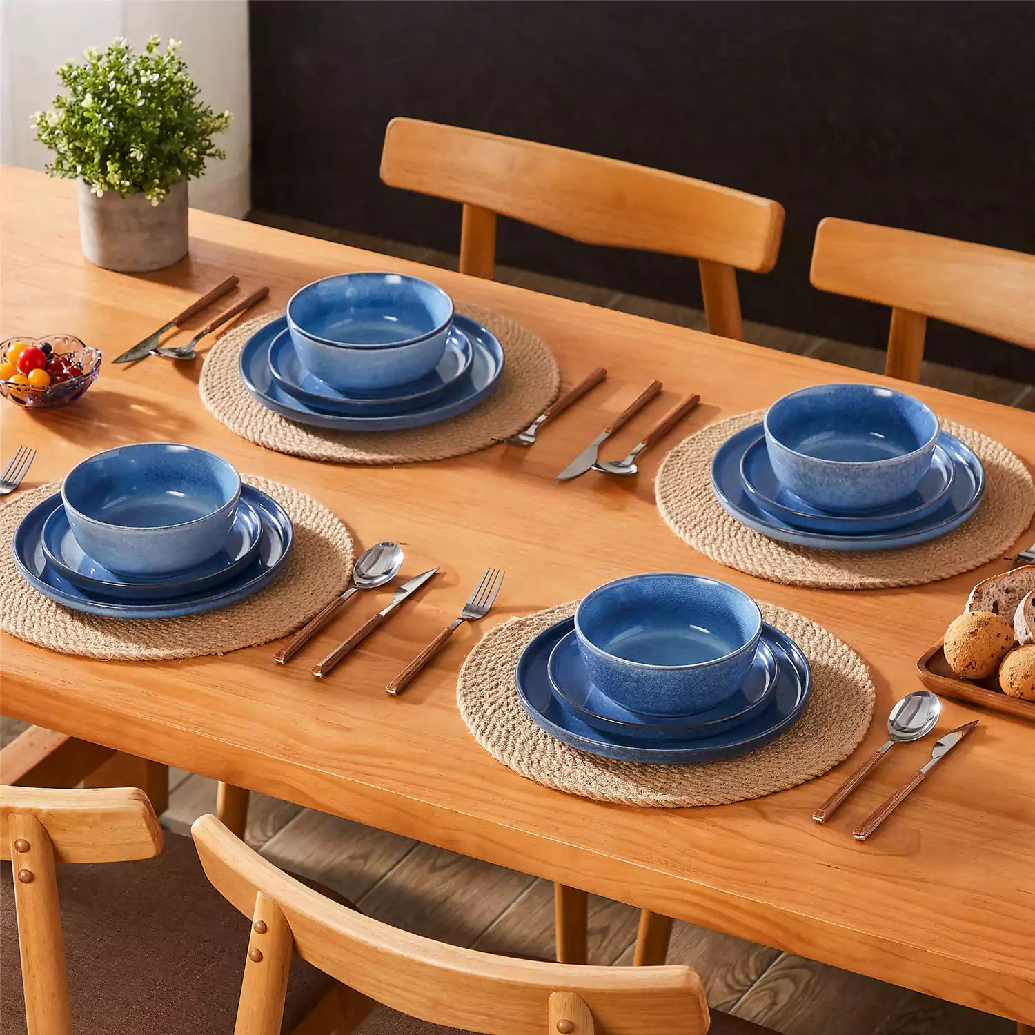 Blue stoneware plates and bowls with reactive glaze on farmhouse wooden table with woven placemats