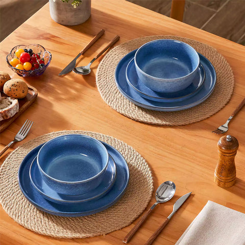 Blue stoneware plates and bowls with reactive glaze on farmhouse wooden table with woven placemats