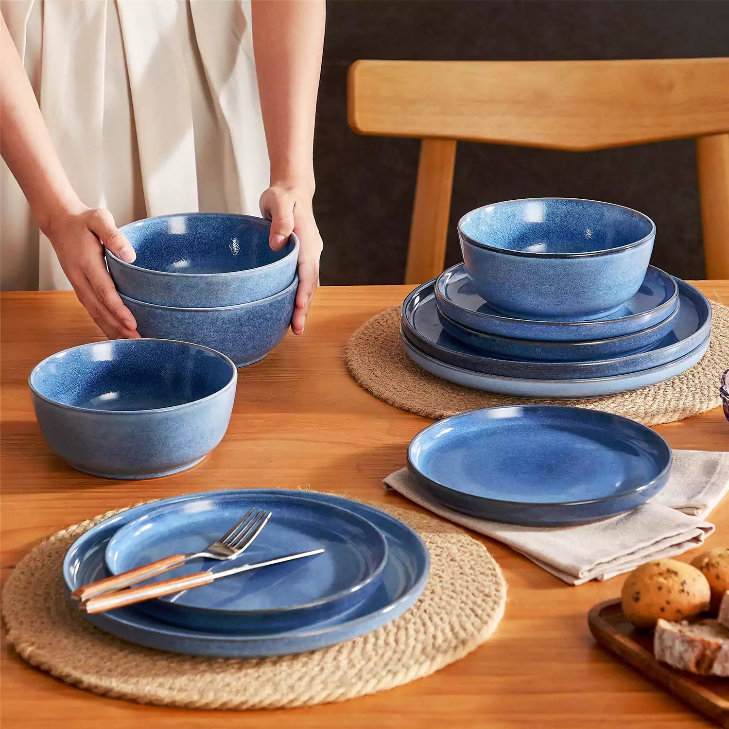 Blue stoneware plates and bowls with reactive glaze on farmhouse wooden table with woven placemats