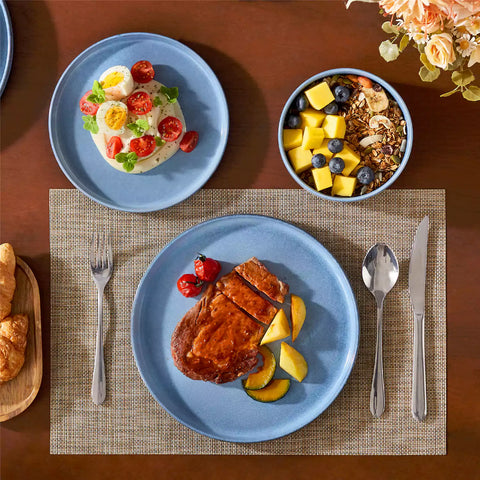 Anya 12 piece straight edge stoneware dinner set in blue with food on a rustic farmhouse wooden table with a side salad and cutlery