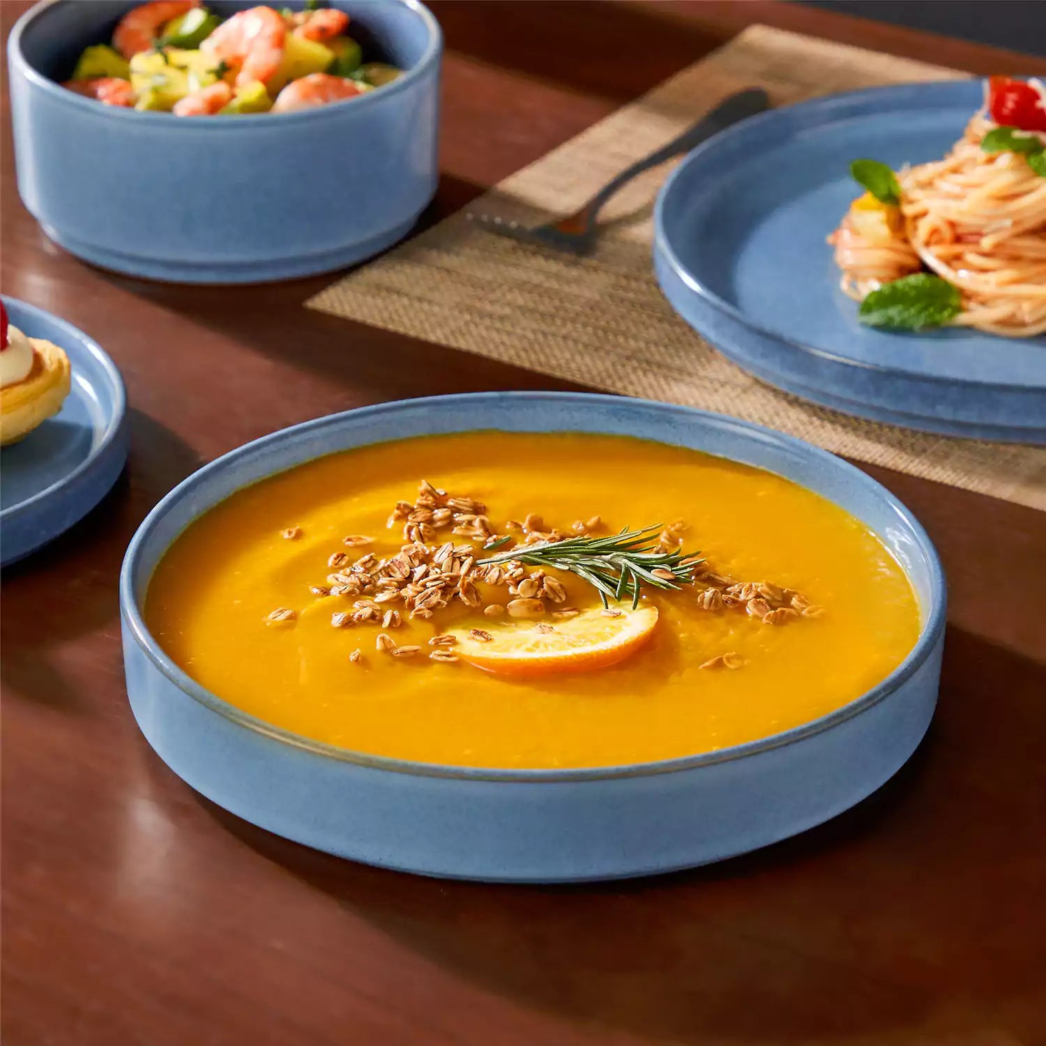 Anya 16 piece straight edge stoneware dinner set in blue with pasta soup and pastries on a modern farmhouse table