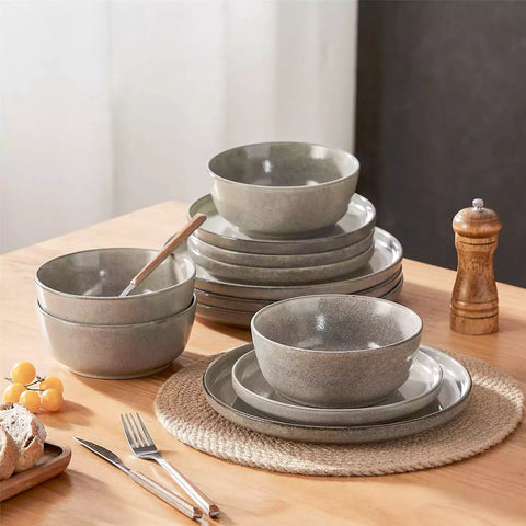 Brown stoneware plates and bowls with reactive glaze on farmhouse wooden table with woven placemats