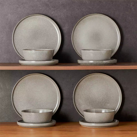 Brown stoneware plates and bowls with reactive glaze on farmhouse wooden table with woven placemats
