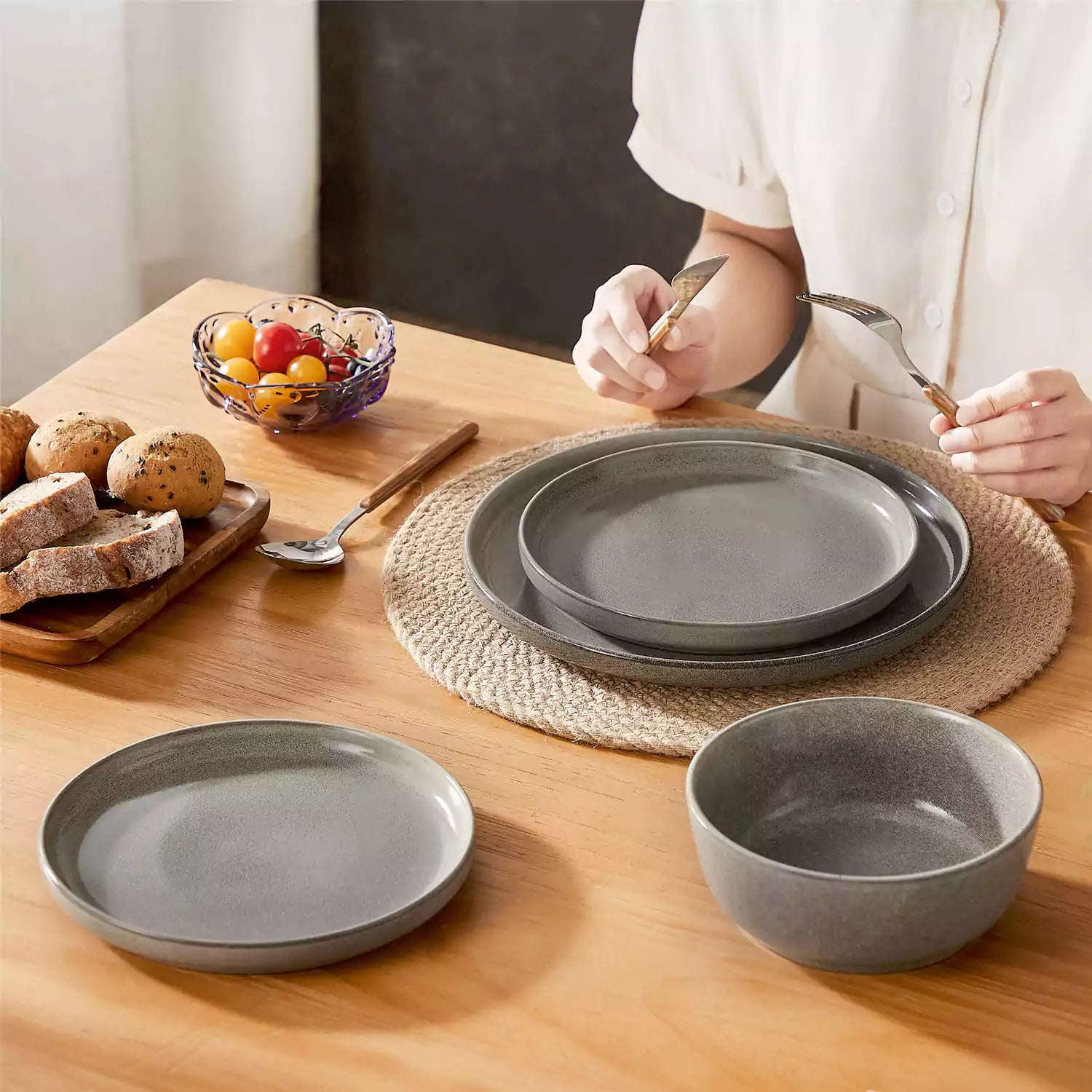 Brown stoneware plates and bowls with reactive glaze on farmhouse wooden table with woven placemats
