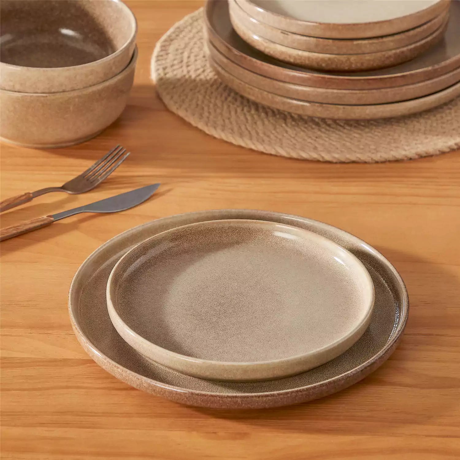 Caramel stoneware plates and bowls with reactive glaze on farmhouse wooden table with woven placemats