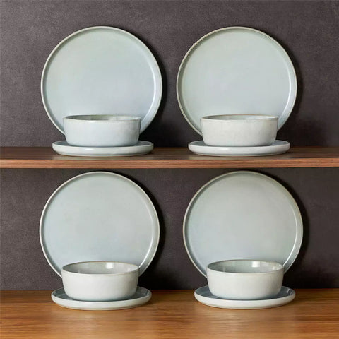 Mint green stoneware plates and bowls with reactive glaze on farmhouse wooden table with woven placemats