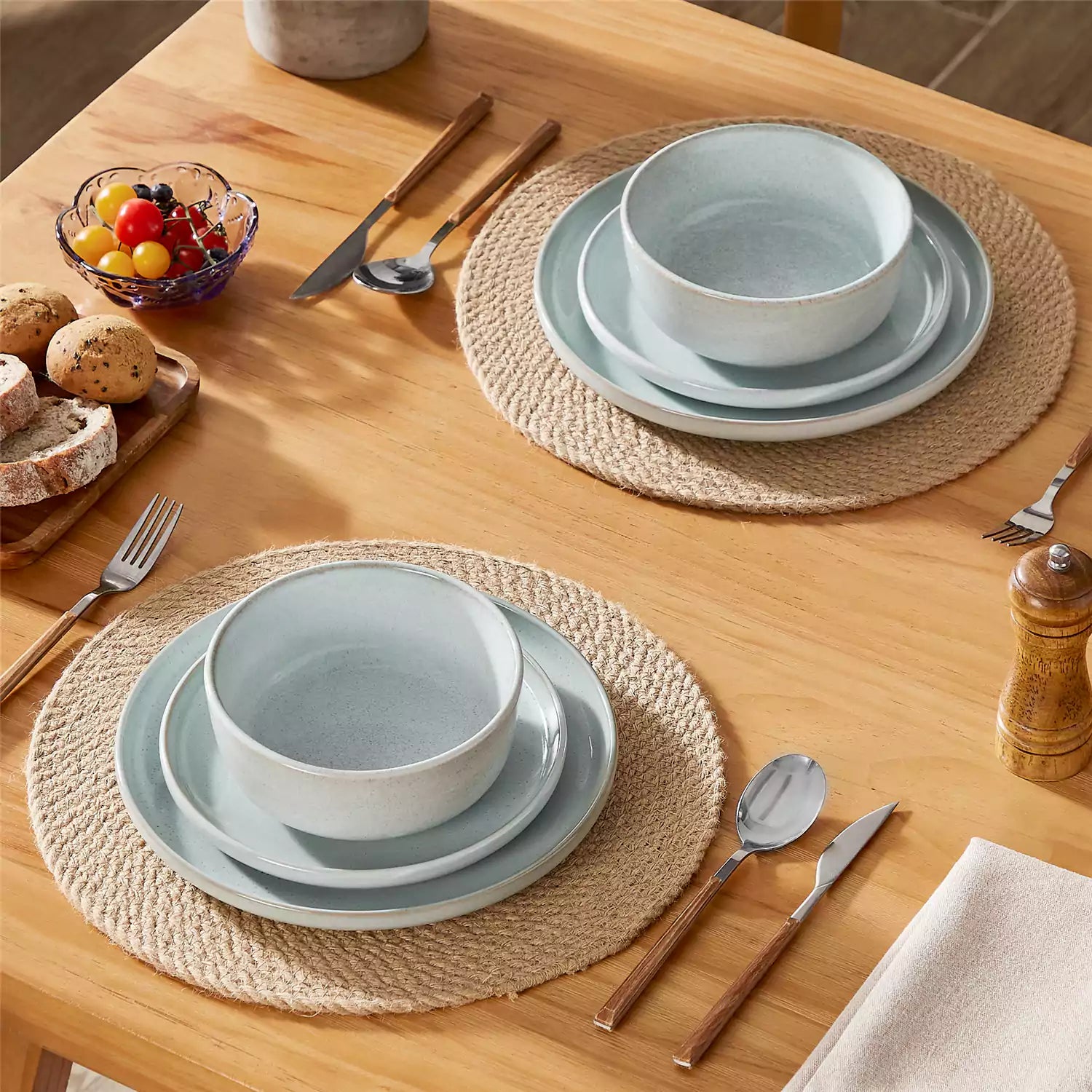 Mint green stoneware plates and bowls with reactive glaze on farmhouse wooden table with woven placemats