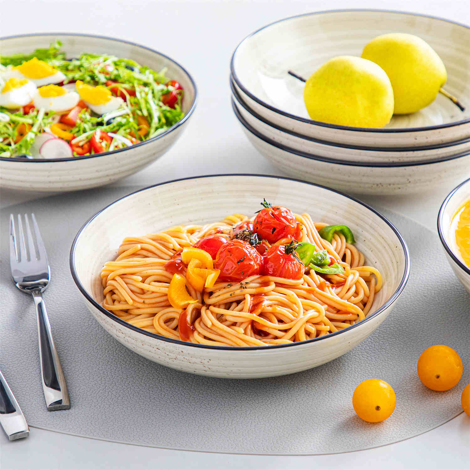 Bonbon double-sided stoneware pasta bowls in beige - artfully filled with pasta - fresh fruit salad - pumpkin soup - and oatmeal - exuding rustic charm on a white dining table