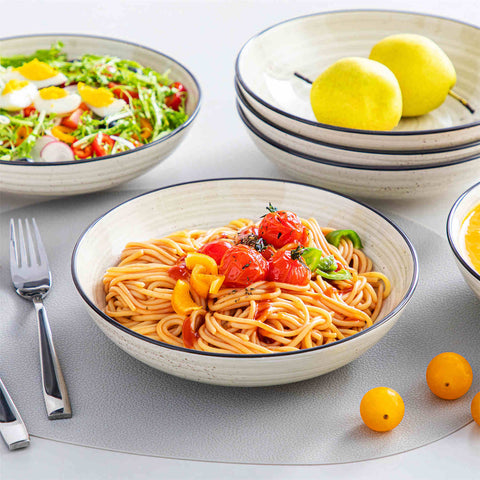 Bonbon double-sided stoneware pasta bowls in beige - artfully filled with pasta - fresh fruit salad - pumpkin soup - and oatmeal - exuding rustic charm on a white dining table