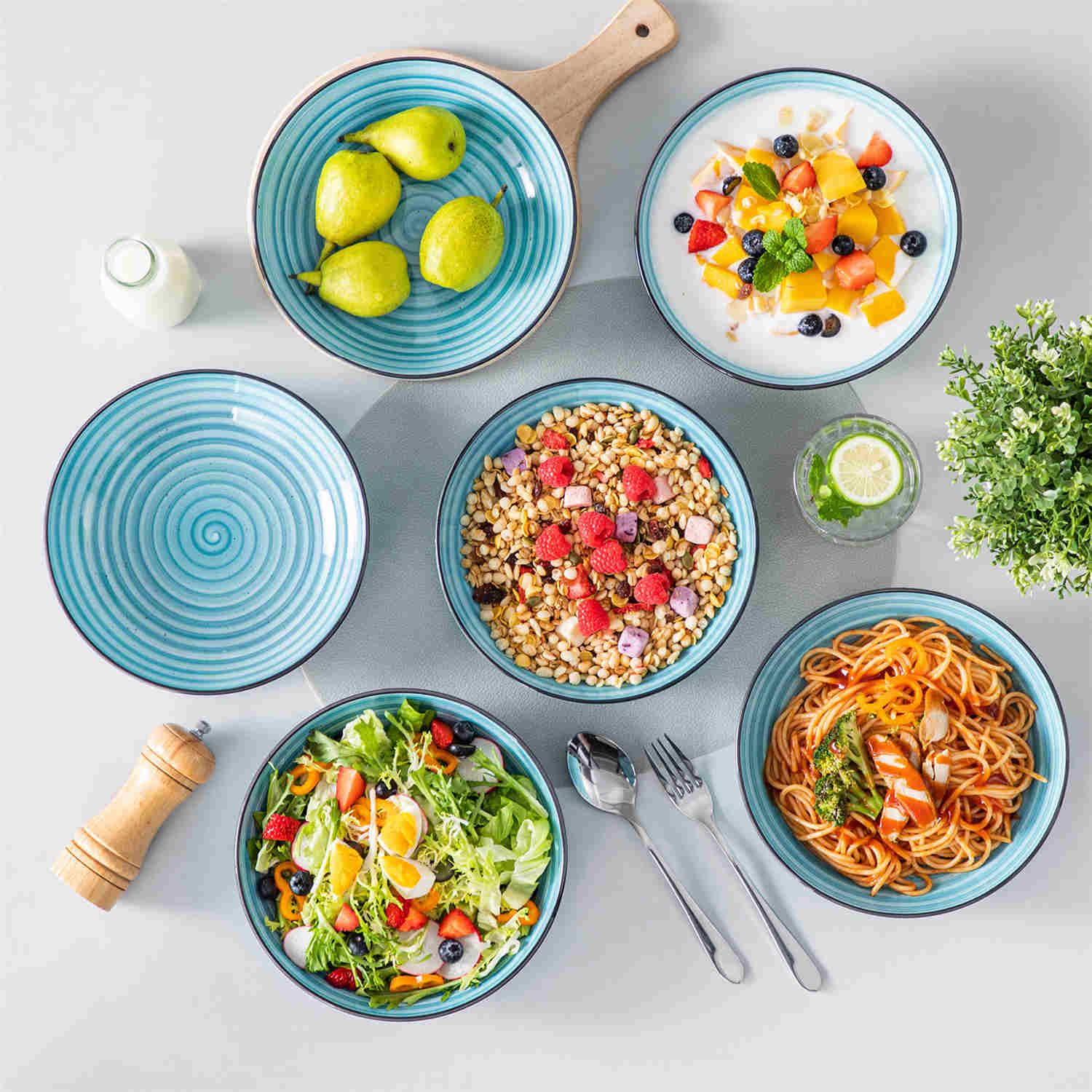 Bonbon double-sided stoneware pasta bowls in blue - artfully filled with pasta - fresh fruit salad - pumpkin soup - and oatmeal - exuding rustic charm on a white dining table