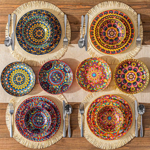 Lumi 24 piece porcelain dinnerware set with vibrant patterns stacked on a wooden table with colorful placemats and assorted dishes