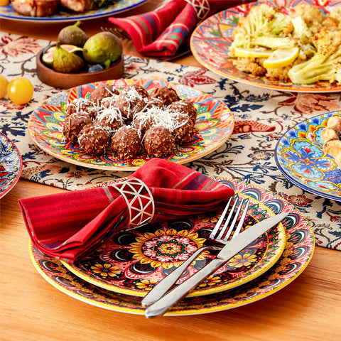 Lumi 12-piece Bohemian dinnerware set for 4 with colorful patterned plates and bowls on a wooden Boho dining table with food