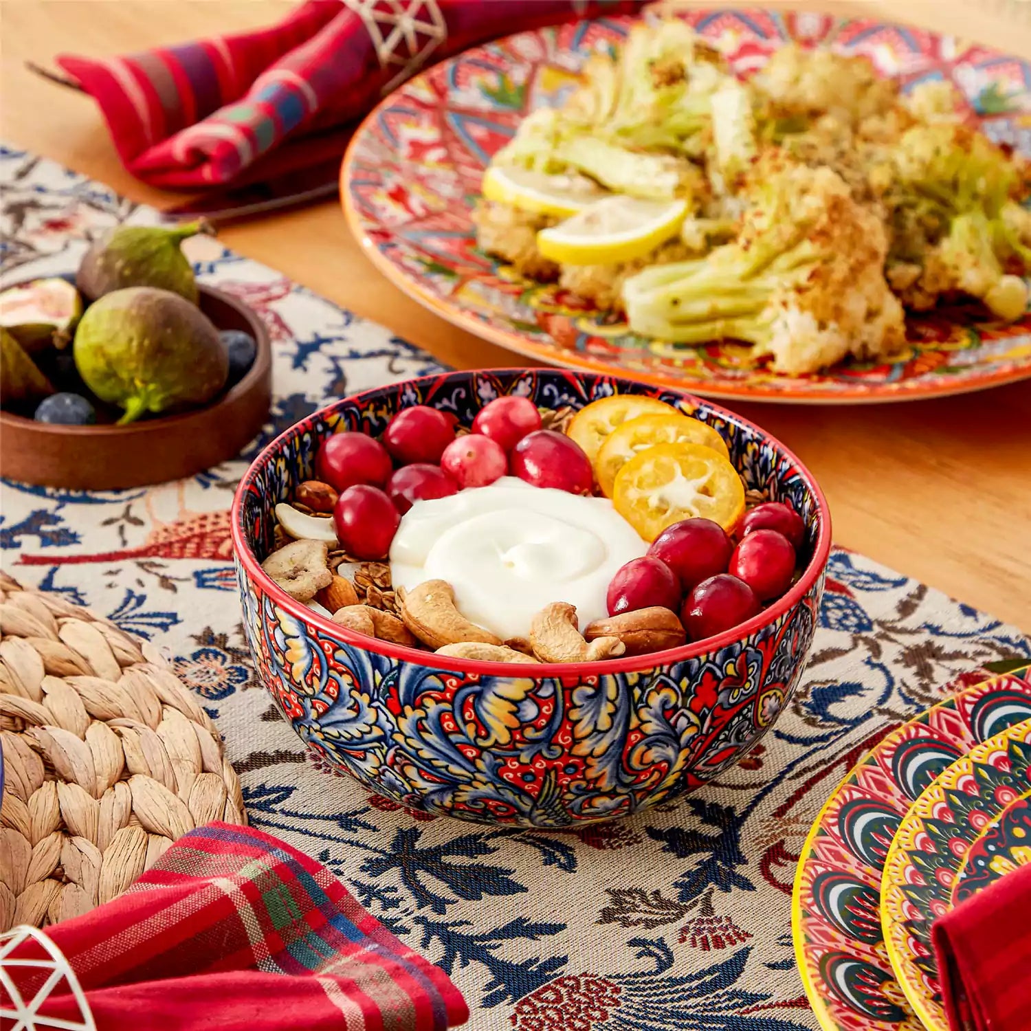Lumi 12-piece Bohemian dinnerware set for 4 with colorful patterned plates and bowls on a wooden Boho dining table with food