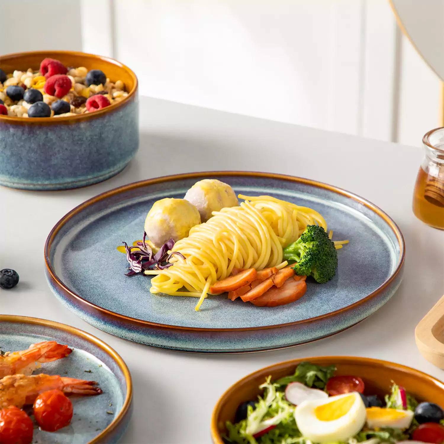 A rustic breakfast spread featuring a plate of meat with vegetables - waffles topped with fruit - and assorted pastries on a white table - complemented by blue stoneware dinnerware