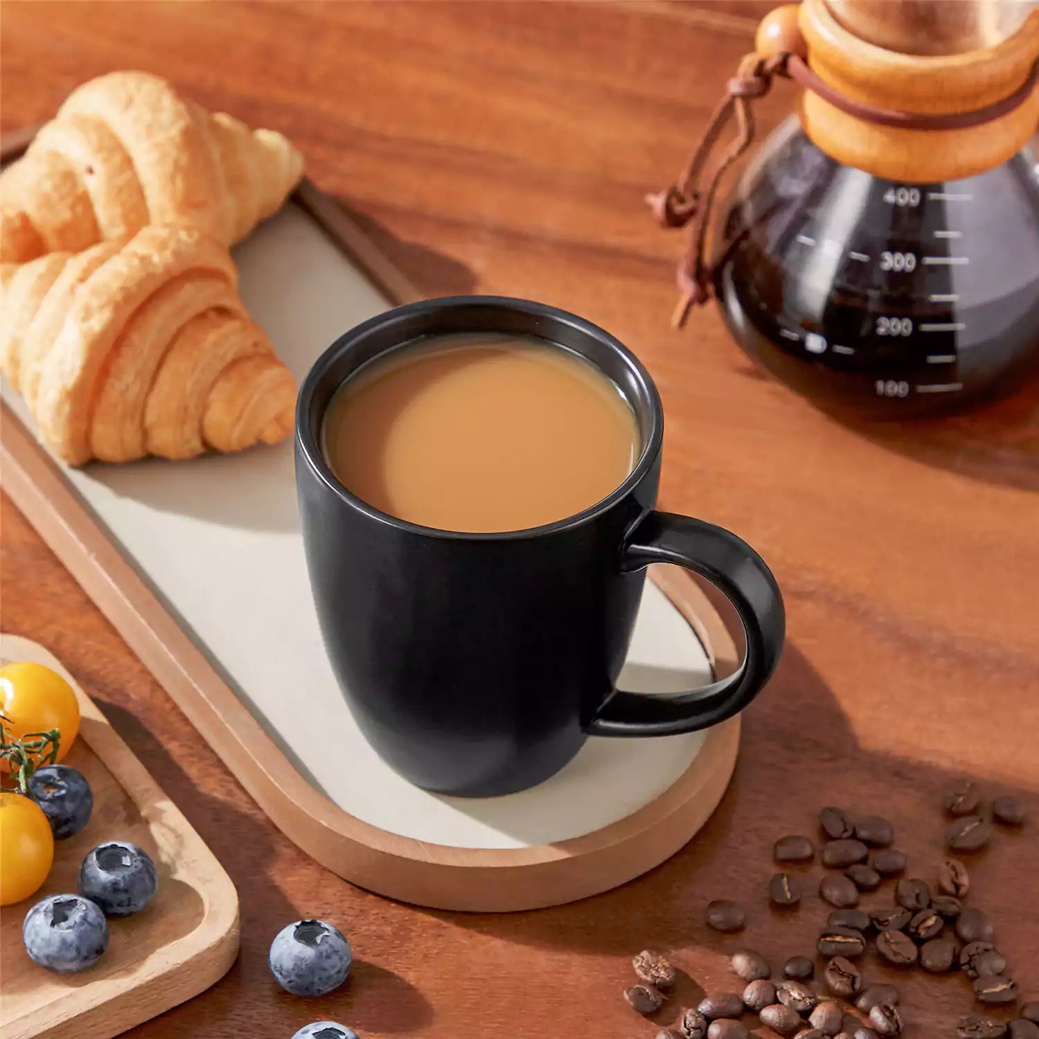 Playa set of four black stoneware mugs and a classic Moka pot on a wooden tray with a morning brew beside fresh pastries and coffee beans