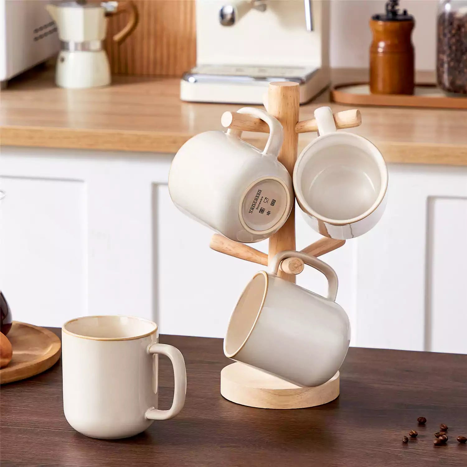 Playa 16oz stoneware mugs in beige reactive glaze on a rustic wooden café table with coffee maker and pastries