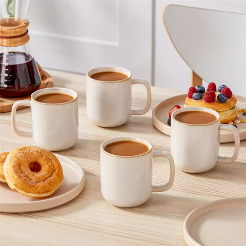 Playa 12oz stoneware mugs in glossy beige reactive glaze on a rustic wooden table for a cozy breakfast with fresh coffee pastries and berries