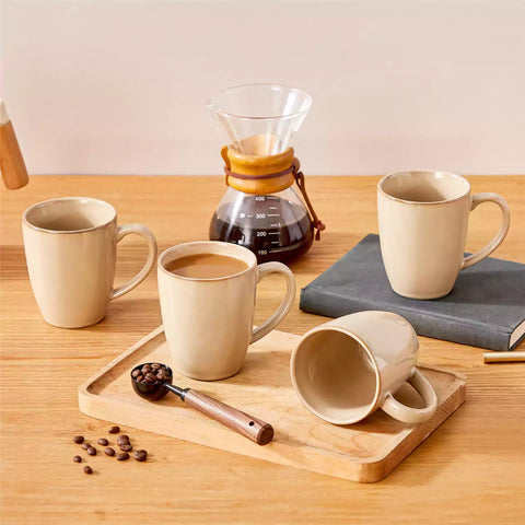 Playa set of four brown reactive glaze stoneware mugs on a wooden tray with a flat white and black coffee beside fresh croissants and berries