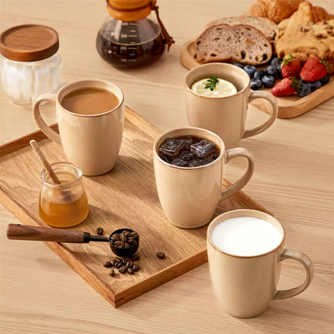 Playa set of four brown reactive glaze stoneware mugs on a wooden tray with a flat white and black coffee beside fresh croissants and berries