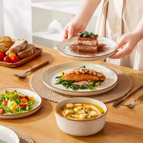Beige rustic stoneware dinnerware set with speckled - lipped-edge plates and bowls on a dining table with flowers and cutlery in a cozy modern kitchen-vancasso