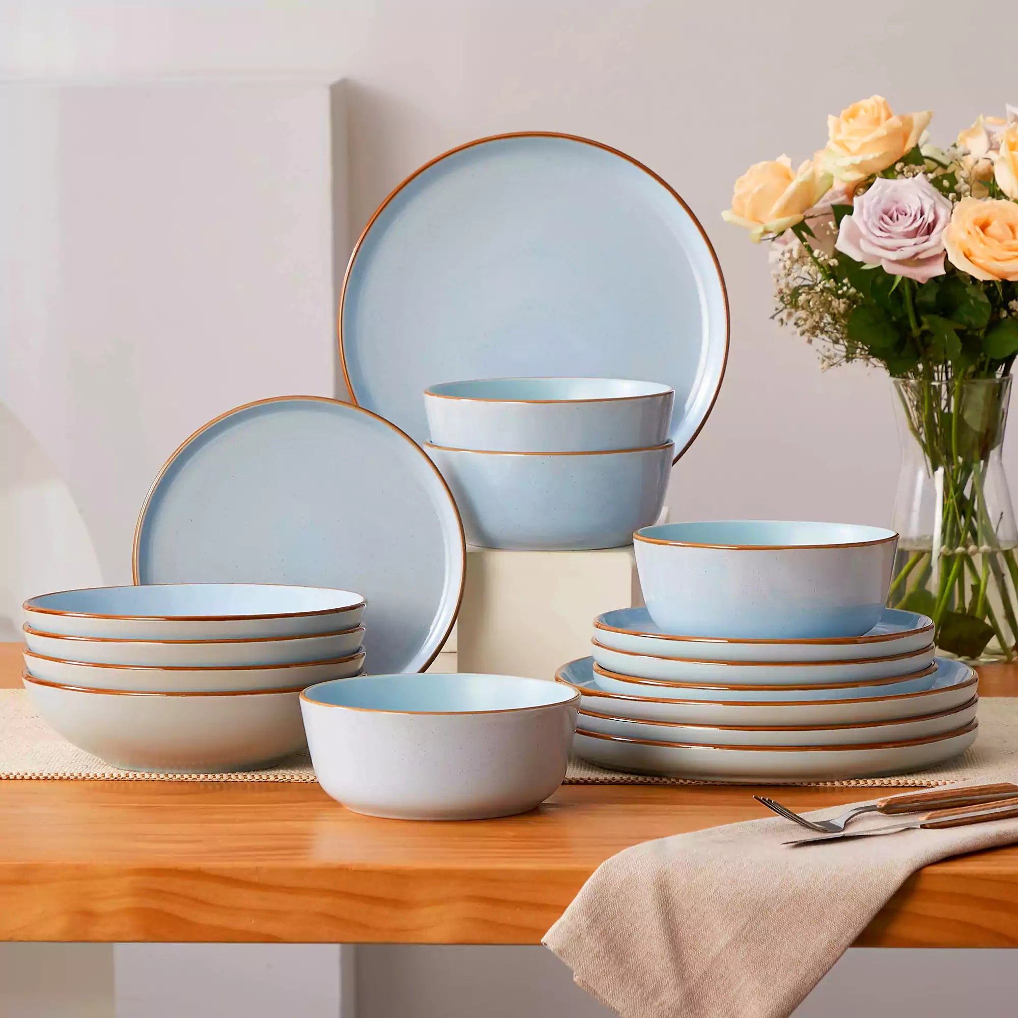 Rustic blue speckled stoneware dinnerware set with lipped-edge plates and bowls arranged on a sunlit modern dining table-vancasso