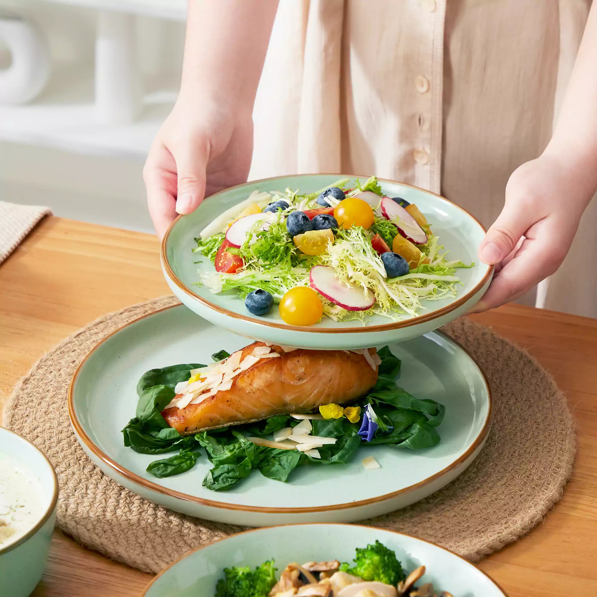 Rustic green speckled stoneware dinnerware set with lipped-edge plates and bowls arranged on a sunlit modern dining table-vancasso