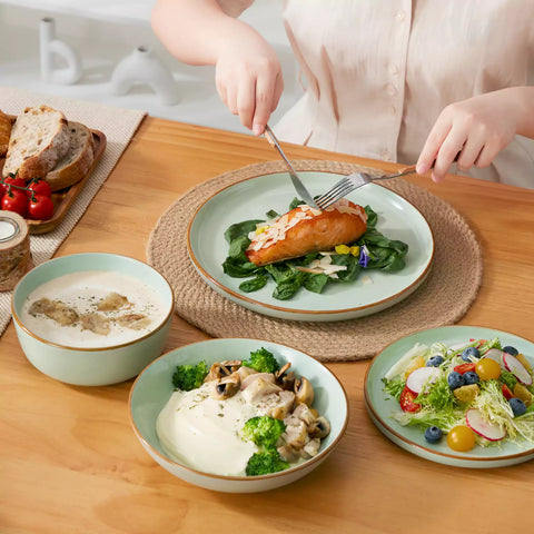 Rustic green speckled stoneware dinnerware set with lipped-edge plates and bowls arranged on a sunlit modern dining table-vancasso