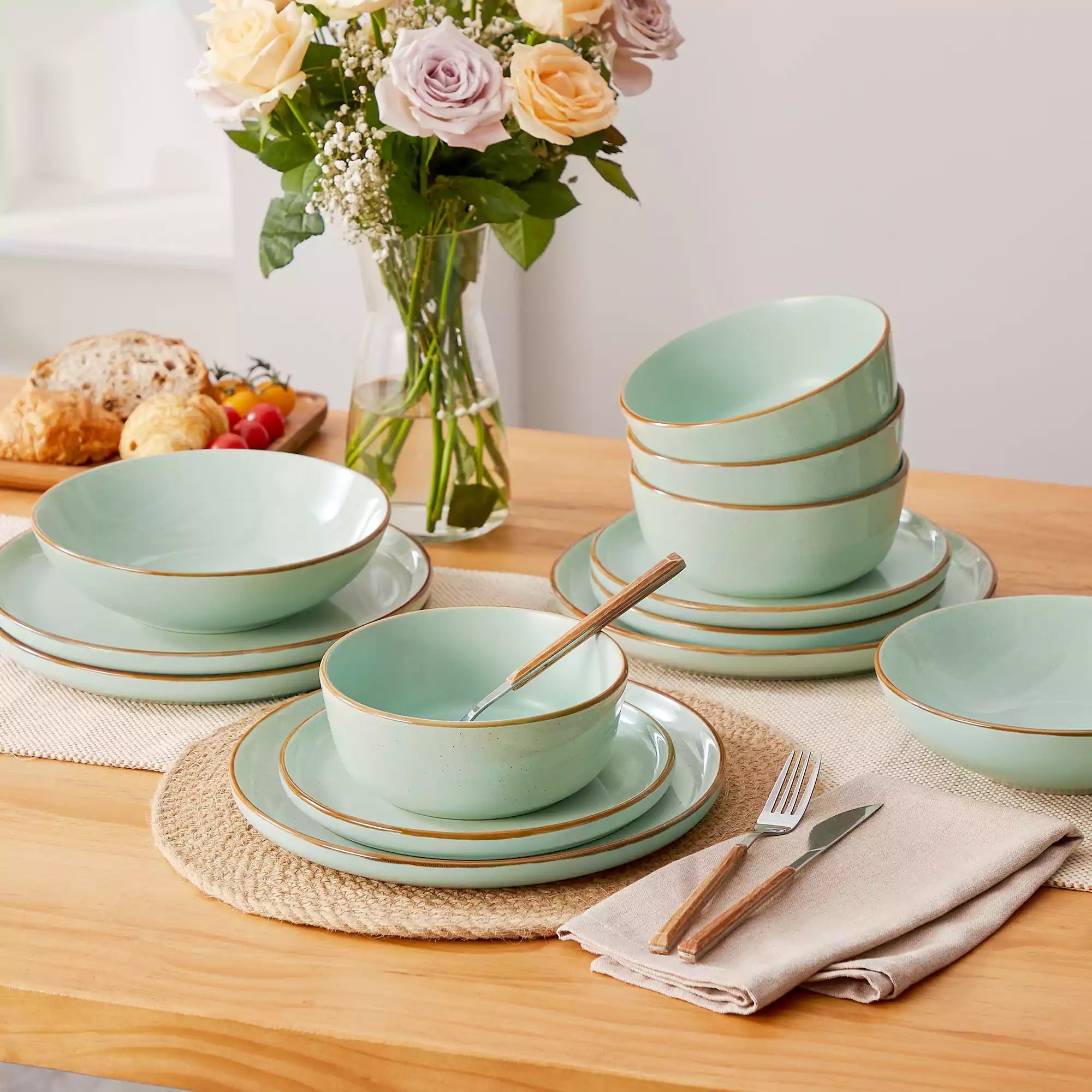 Rustic green speckled stoneware dinnerware set with lipped-edge plates and bowls arranged on a sunlit modern dining table-vancasso