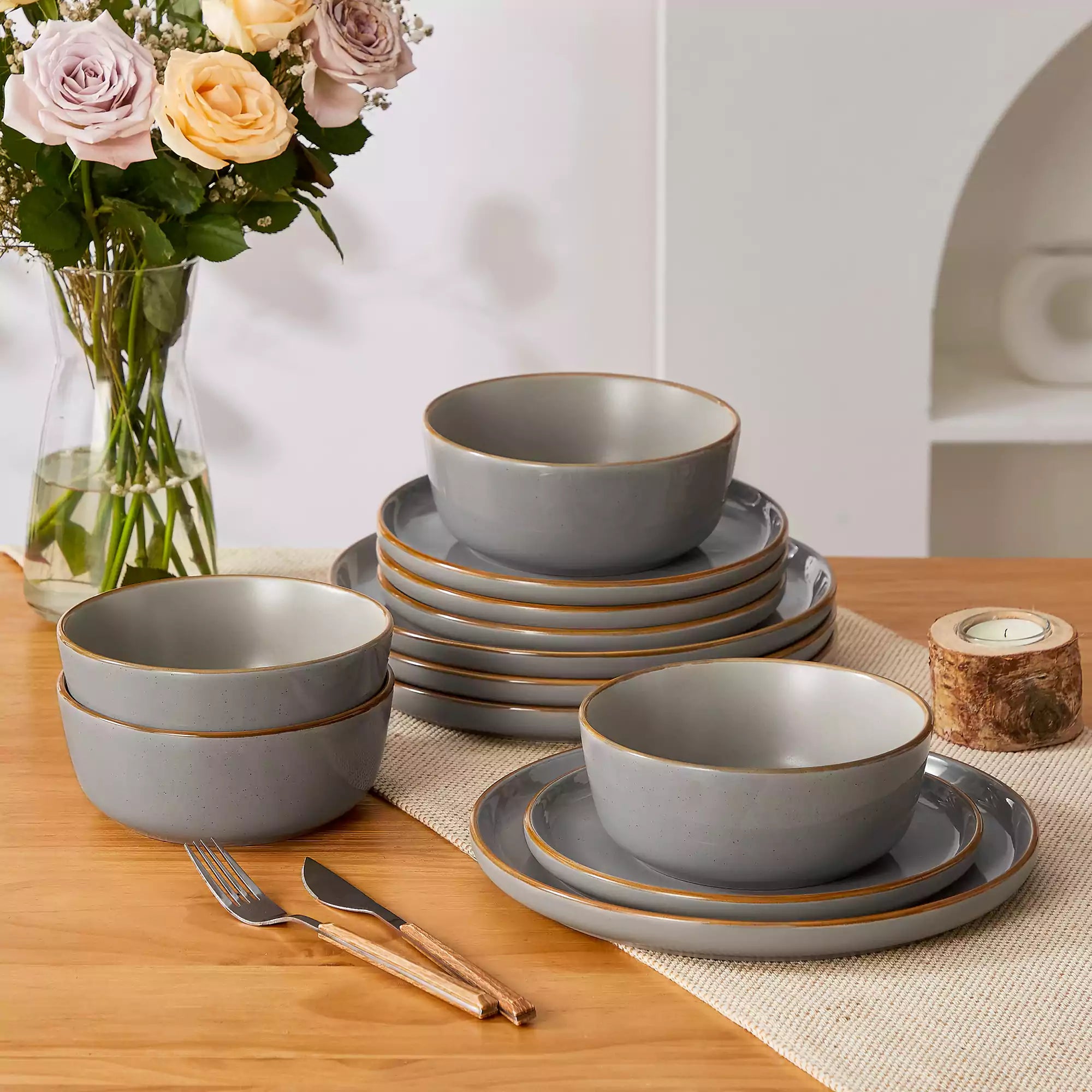 Grey rustic stoneware dinnerware set with speckled - lipped-edge plates and bowls on a dining table with flowers and cutlery in a cozy modern kitchen-vancasso