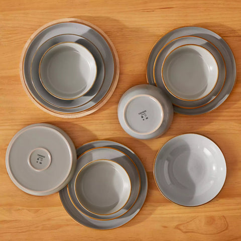 Rustic grey speckled stoneware dinnerware set with lipped-edge plates and bowls arranged on a sunlit modern dining table-vancasso