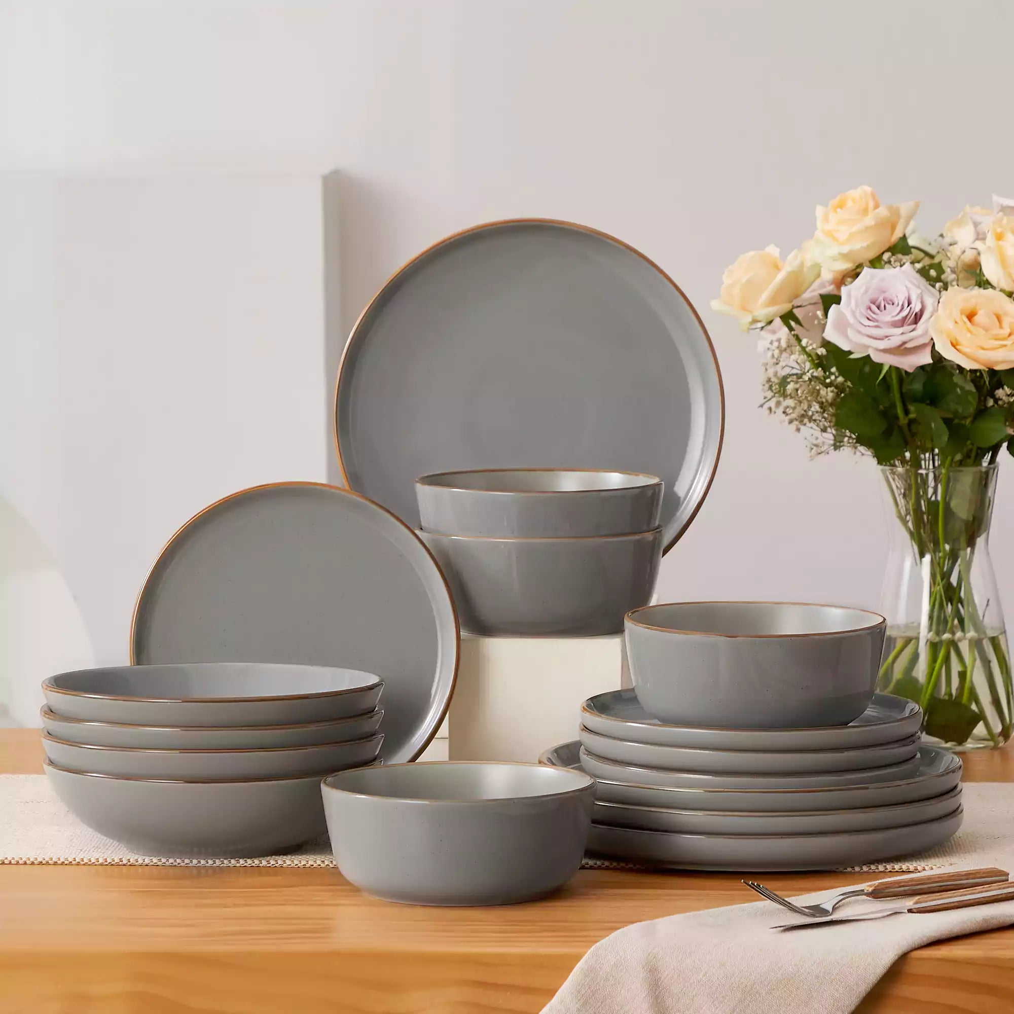 Rustic grey speckled stoneware dinnerware set with lipped-edge plates and bowls arranged on a sunlit modern dining table-vancasso