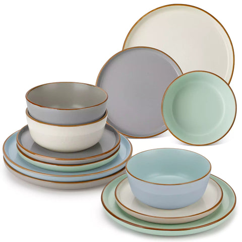 Assorted rustic stoneware dinnerware set with speckled - lipped-edge plates and bowls on a dining table with flowers and cutlery in a cozy modern kitchen-vancasso