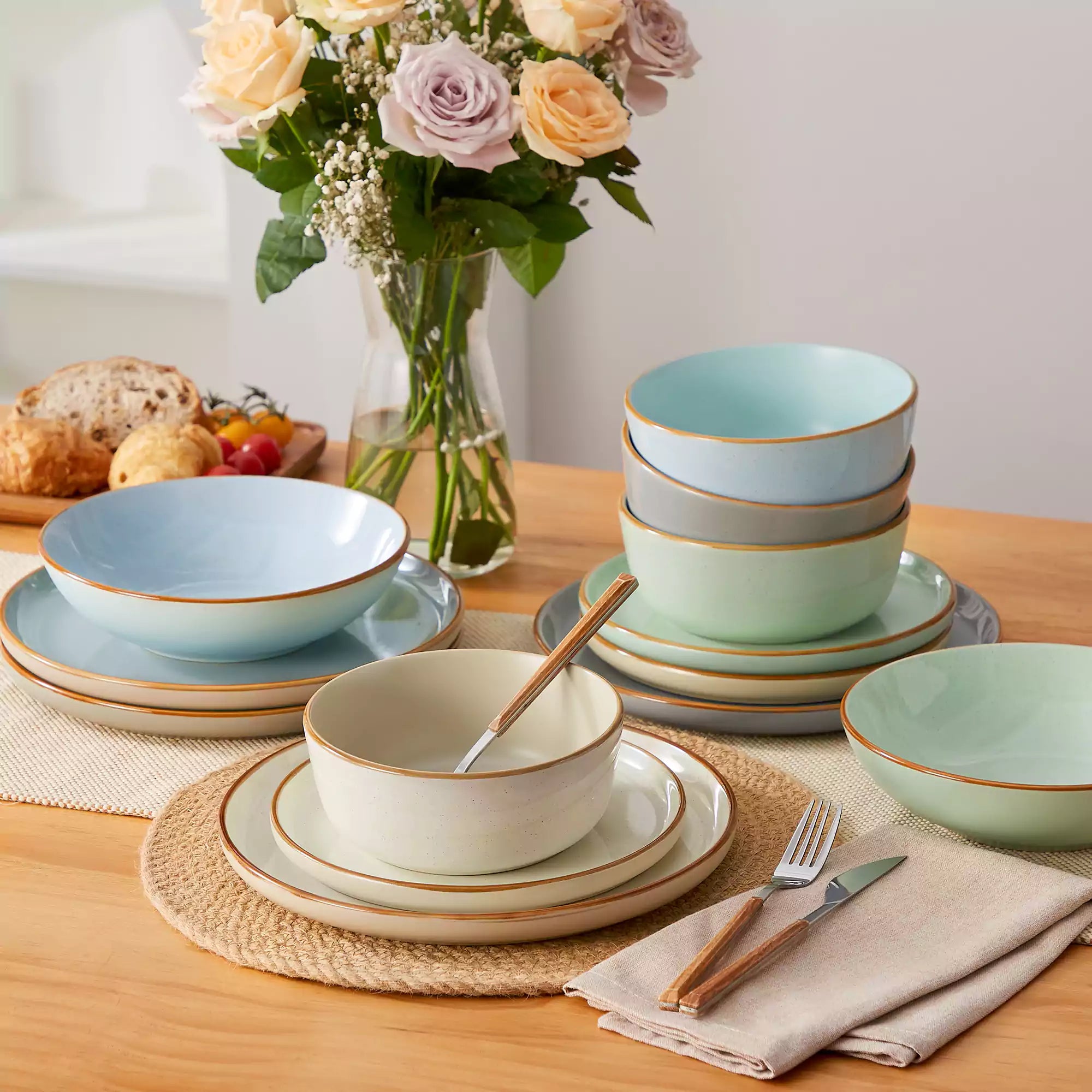 Rustic assorted speckled stoneware dinnerware set with lipped-edge plates and bowls arranged on a sunlit modern dining table-vancasso