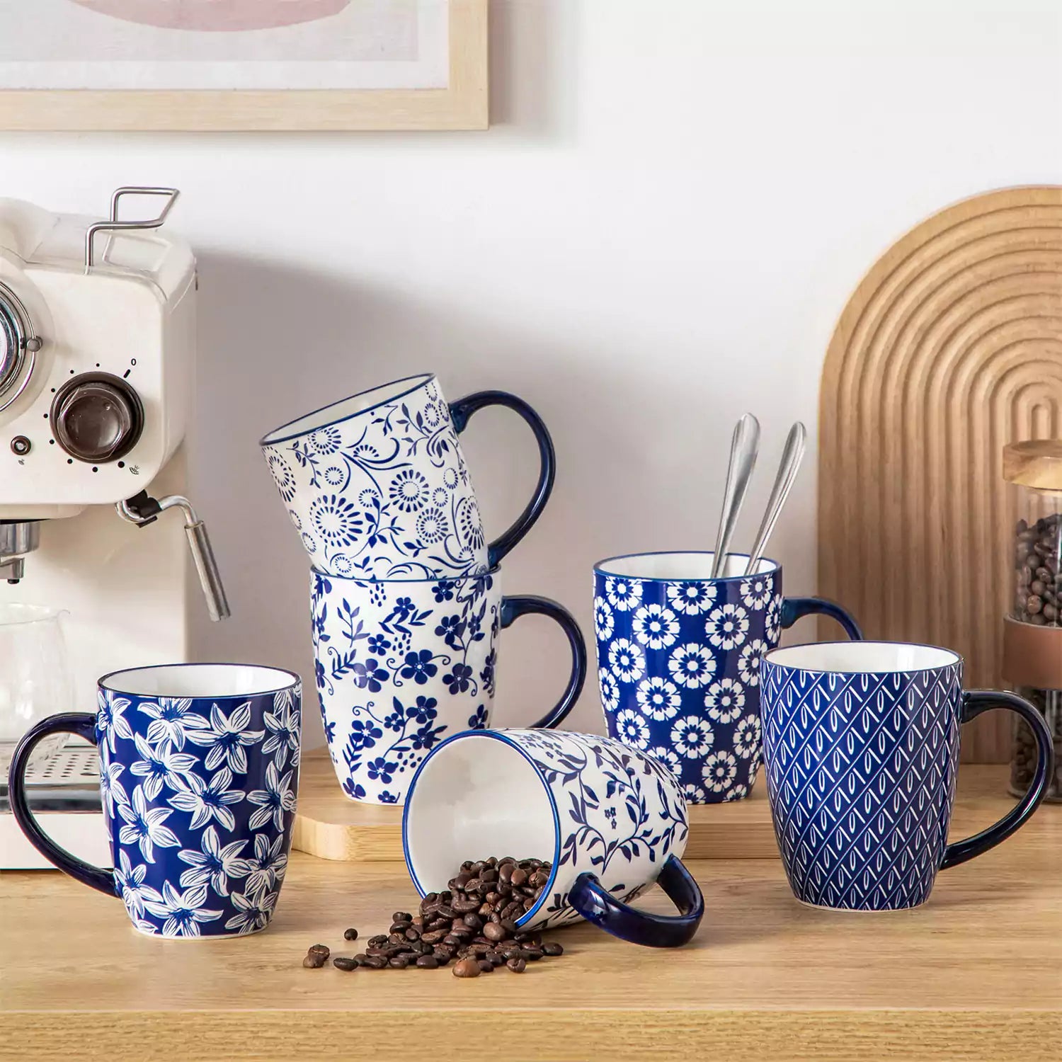 Set of six Japanese-style stoneware mugs in blue and white with indigo patterns, displayed on a kitchen counter with scattered coffee beans