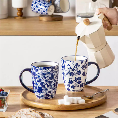 Set of six Japanese-style stoneware mugs in blue and white with indigo patterns, displayed on a kitchen counter with scattered coffee beans