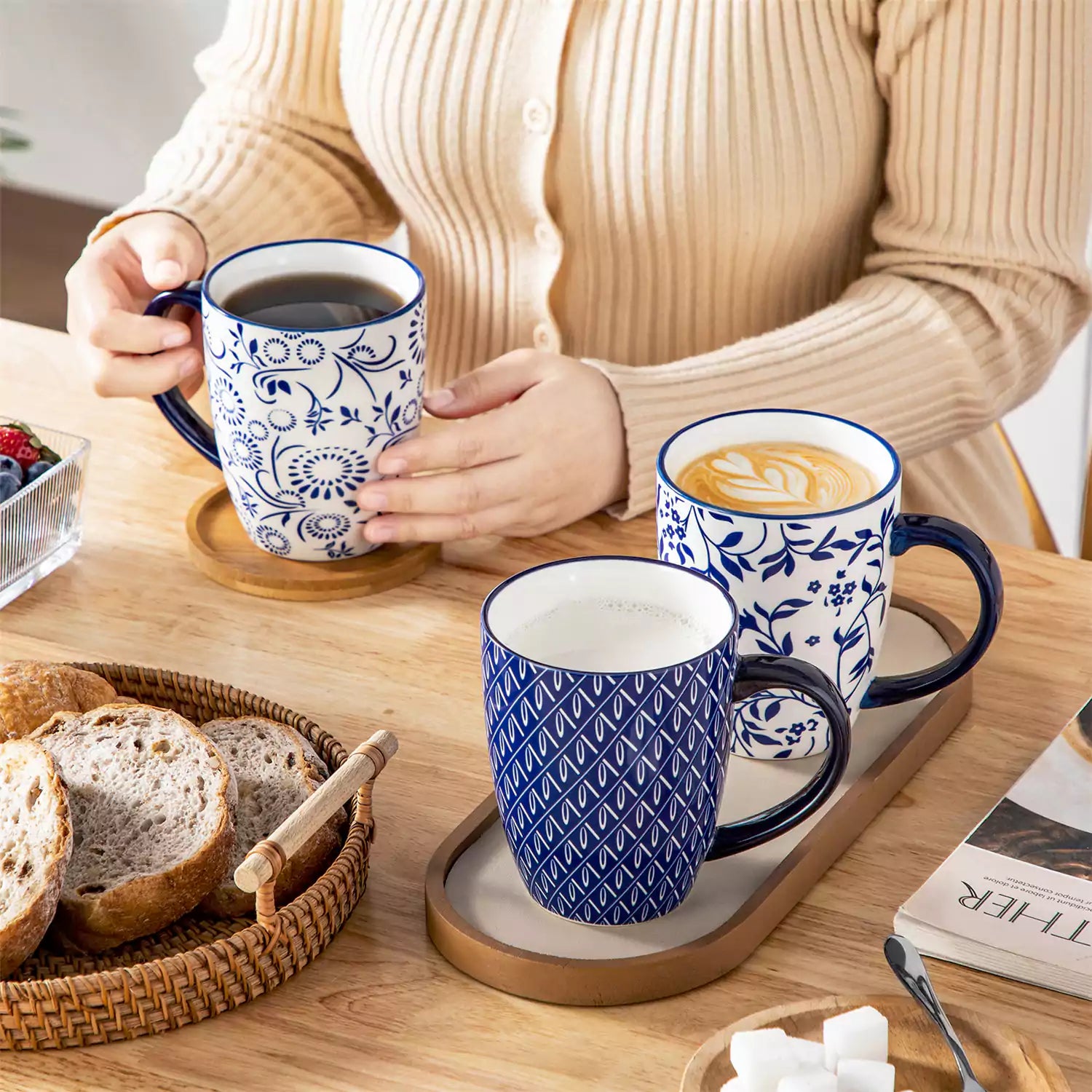 Set of six Japanese-style stoneware mugs in blue and white with indigo patterns, displayed on a kitchen counter with scattered coffee beans