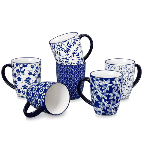 Set of six Japanese-style stoneware mugs in blue and white with indigo patterns, displayed on a kitchen counter with scattered coffee beans