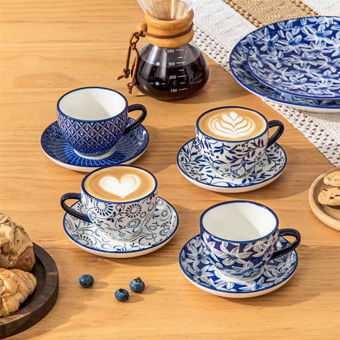 Set of 4 Selene indigo floral porcelain cups and saucers on a wooden table with coffee and pastries featuring blue and white Japanese style mix and match patterns