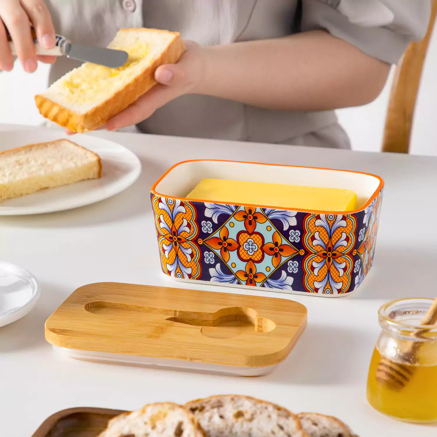 Bold orange porcelain butter dish with wooden lid in boho chic style - perfect for a colorful breakfast table with bread and coffee-vancasso